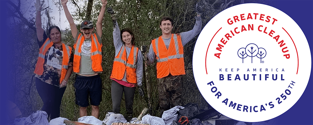 Banner artwork: four people in orange safety vests raise their arms in celebration in front of scrubby trees, with filled rubbish sacks and collected debris at their feet, beside the round Keep America Beautiful cleanup seal.