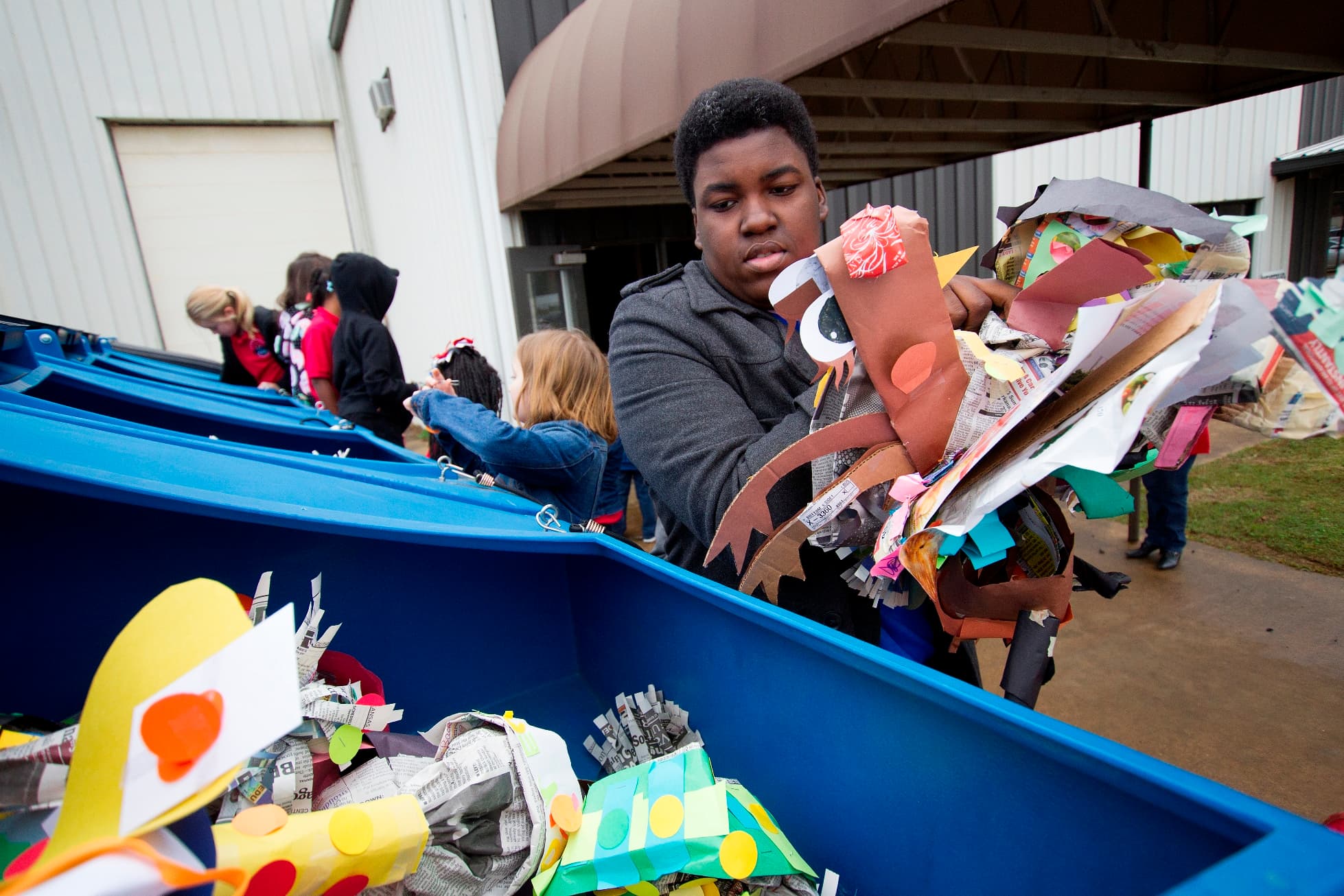 A community recycling drop-off in progress, with volunteers guiding cars and unloading sorted materials.